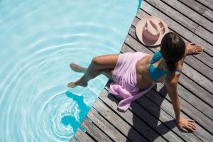 a woman in a hat laying on a wooden pier next to the water at Solana Beach Mauritius - Adults Only in Belle Mare