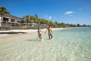 a man and woman walking in the water on a beach at Solana Beach Mauritius - Adults Only in Belle Mare
