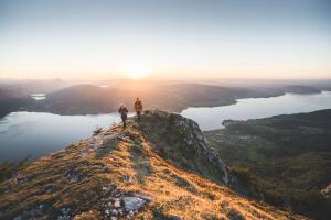 two people standing on top of a mountain at sunset at Hotel Das Zeit in Lenzing