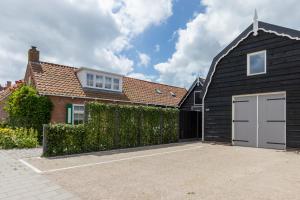 una casa negra con un garaje blanco en Welcome in - Vakantiewoning met sauna en zonnig terras, en Biggekerke