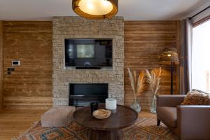 a living room with a fireplace with a tv and a table at Apache_Coudriers in Megève