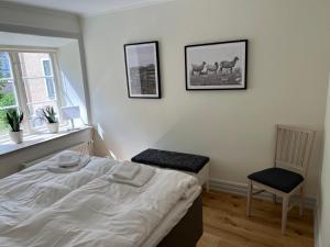 a bedroom with a bed and a chair and a window at Apartments Strandgatan Visby in Visby