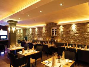a restaurant with tables and chairs and a stone wall at Schloss Hotel Burgbrohl in Burgbrohl