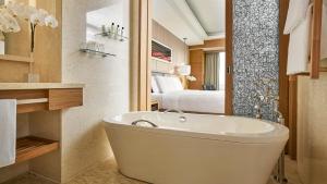 a bathroom with a bath tub and a bedroom at InterContinental Saigon, an IHG Hotel in Ho Chi Minh City