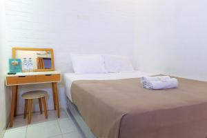 1 dormitorio con cama y escritorio con espejo en Griya Ayem en Srondolwetan