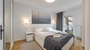 a white bedroom with a bed with two towels on it at Apartamenty Sun & Snow Baltic Park II in Pogorzelica