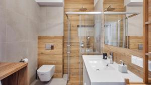 ein Bad mit einem WC, einem Waschbecken und einer Dusche in der Unterkunft Apartamenty Sun & Snow Baltic Park II in Pogorzelica