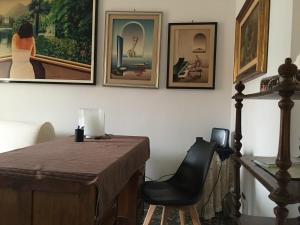Habitación con mesa, silla y cuadros en la pared. en Casa Lorusso, en Bari