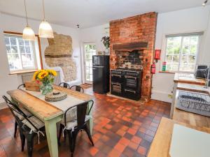 a kitchen with a table and a brick fireplace at Old Rectory Cottage in Lincoln