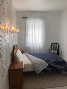 a bedroom with a bed with a blue blanket and a window at Pensión Barqueiras 15 in O Grove