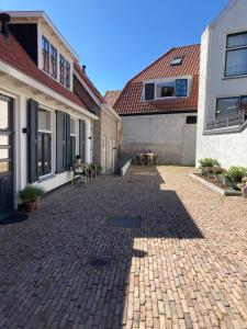 a brick courtyard with a table and a building at Guesthouse Bonniehofje in Zandvoort