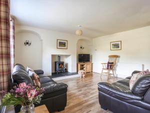 a living room with a leather couch and a fireplace at Ty Coch in Caernarfon