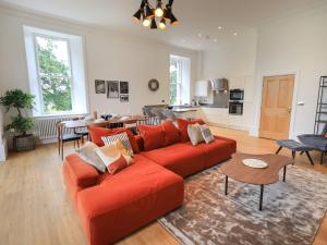Il comprend un salon avec un canapé rouge et une cuisine. dans l'établissement The Kathleen Suite Stone Cross Mansion, à Ulverston