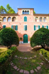 Un gran edificio rosa con una puerta verde y dos arbustos. en Comfortable Apartment in Fabriano, 35 m² with Shared Pool, en Fabriano