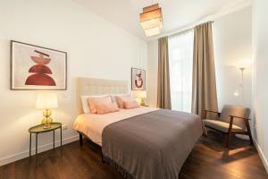 a bedroom with a bed and a chair and a window at Foz Beach House - Rooftop & Sea view in Foz do Arelho +37 photos