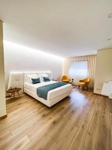 una camera da letto con un grande letto bianco e pavimenti in legno di Encosta do Monte a Ponte de Lima