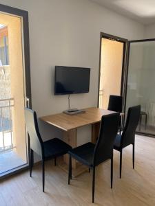 a wooden table with chairs and a television on top at Appartements neufs avec garages dans maison de village in Andance