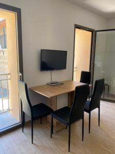 une table en bois avec des chaises et une télévision sur le dessus dans l'établissement Appartement neuf avec garage, à Andance