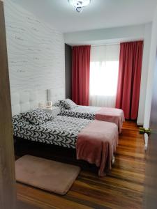 two beds in a bedroom with red curtains at Vivienda turística Mou in Arzúa