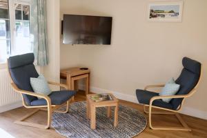 a living room with two chairs and a tv at Lawnside 2 in Budleigh Salterton