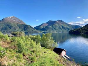 una pequeña casa a orillas de un lago con montañas en Apartment Halsanaustan, en Korsnes