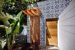 a small house with a wooden door in a garden at Dolphin Coast YOLO Spaces - The White House Boutique Villa in Sheffield Beach