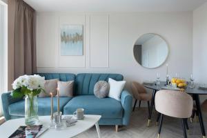 a living room with a blue couch and a table at Elite Apartments Marine Cztery Oceany in Gdańsk