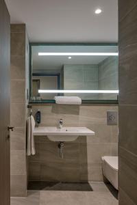 a bathroom with a sink and a toilet and a mirror at Maldron Hotel Manchester City Centre in Manchester