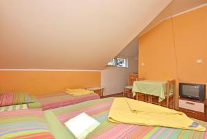 two beds in a room with a tv and a table at Apartments Kujacic in Herceg-Novi