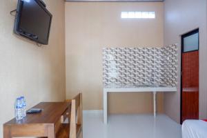 a living room with a tv and a table at RedDoorz Syariah near Stasiun Gumilir Cilacap in Gumilir +18 photos