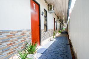 an alley way with plants and a red door at RedDoorz Syariah near Stasiun Gumilir Cilacap in Gumilir