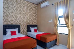 a bedroom with two beds and a window at RedDoorz Syariah near Stasiun Gumilir Cilacap in Gumilir