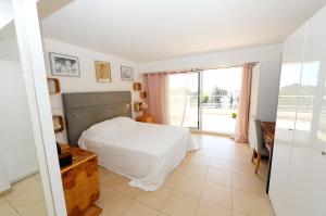 een slaapkamer met een bed en een groot raam bij Villa Les Voiles in Cannes