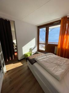 a bedroom with a bed and two large windows at Superbe appartement vue panoramique pied des pistes in La Mongie