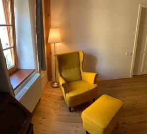 a living room with a yellow chair and a ottoman at Apartmány Zámecká in Moravská Třebová