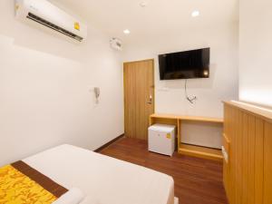 a room with a bed and a desk and a tv at Watergate City in Bangkok