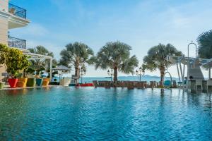 una piscina en un complejo con palmeras en LK Emerald Beach - SHA Extra Plus en Pattaya North