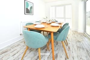 uma sala de jantar com uma mesa de madeira e cadeiras azuis em Ivory House by Truestays - 3 Bedroom House in Stoke-on-Trent em Etruria