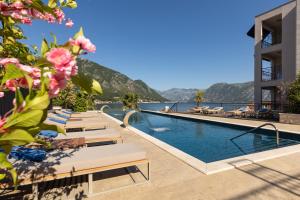 uma piscina do hotel com espreguiçadeiras e vista para o oceano em HUMA Kotor Bay Hotel and Villas em Kotor