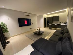 a living room with a large couch and a tv at 3 - Bedroom Apartment in Riyadh