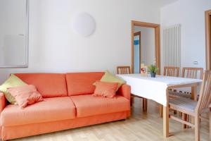 uma sala de estar com um sofá laranja e uma mesa branca em Incantevole appartamento con parcheggio gratuito em Trento