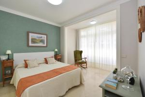 a bedroom with a bed and a chair and a window at Apartment Las Canteras Beach in Las Palmas de Gran Canaria