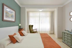 a bedroom with a bed and a chair and a window at Apartment Las Canteras Beach in Las Palmas de Gran Canaria