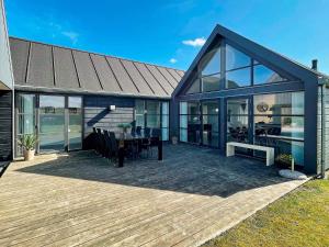 ein Haus mit einer Terrasse mit einem Tisch und Stühlen in der Unterkunft 12 person holiday home in Hadsund in Nørre Hurup