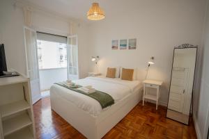 um quarto branco com uma cama e um espelho em The Av. Roma Apartment em Lisboa