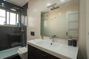 uma casa de banho com um lavatório, um espelho e um WC. em The Av. Roma Apartment em Lisboa