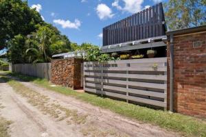 a fence next to a dirt road with a building at Buhwi Bira Byron Bay - Studio in Byron Bay