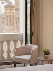 a white chair sitting in front of a window at Hotel Oriente in Zaragoza