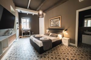 een slaapkamer met een bed, een televisie en een bureau bij Palazzo Paladini - Luxury Suites in the Heart of the Old Town in Pizzo