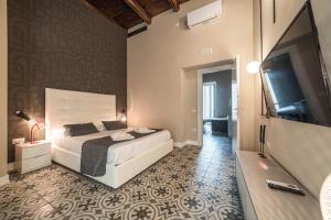 een slaapkamer met een bed en een flatscreen-tv bij Palazzo Paladini - Luxury Suites in the Heart of the Old Town in Pizzo